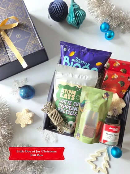 A closer look at the Little Box of Joy Christmas Gift Box. This compact hamper includes white chocolate peppermint pretzels and other festive snacks in a beautiful navy blue box.