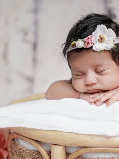 A close-up portrait showing the baby's sweet, sleeping face and the delicate details of her floral headband.
