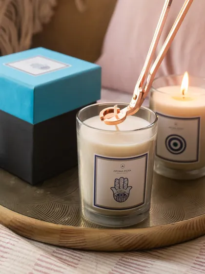 A close-up of our Hamsa candle being tended to with a wick trimmer. This image highlights the protective symbol and the importance of candle care to ensure a clean, long-lasting burn.