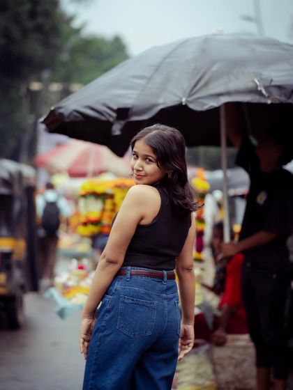 A candid over-the-shoulder look. The umbrella adds a nice compositional element and a hint of story to this monsoon street portrait.