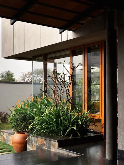 The covered verandah provides a shaded transition space, with planters and a water body cooling the air before it enters the home.