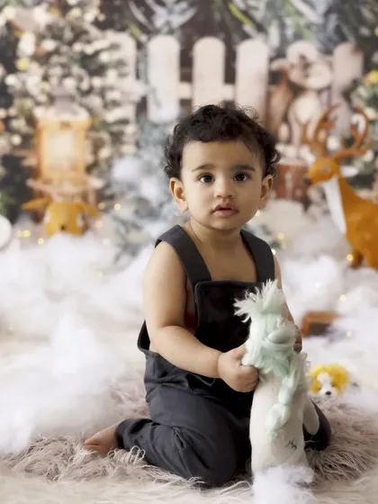 Holding a favorite toy in a magical Christmas scene. Our festive setups are filled with detailed props to create an immersive and enchanting experience for your child's holiday photoshoot.