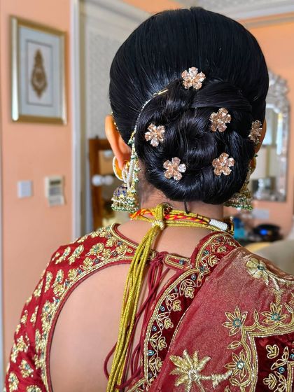 A detailed shot of the neat, interwoven bun decorated with small gold floral pins, a subtle yet elegant choice.