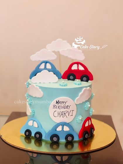 A simple and cute car-themed cake. This light blue cake is decorated with fondant cars and clouds, making it a great choice for a toddler's birthday party.
