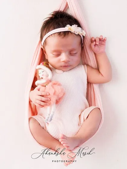 Even the tiniest clients have their favorite companions. This little one is peacefully dreaming in a soft pink sling, holding her little doll, adding a touch of personal sweetness to her first photoshoot.