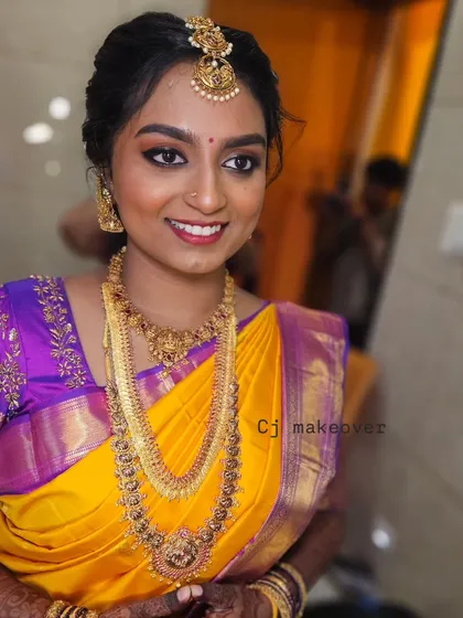 A smiling bride in her yellow and purple muhurtham saree. The makeup is fresh and bright, matching her happy mood.