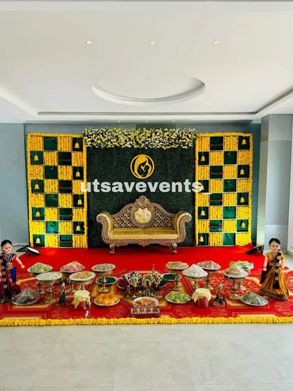 A wide shot of a baby shower in a convention hall, featuring the popular green and yellow checkered backdrop with a traditional golden divan.