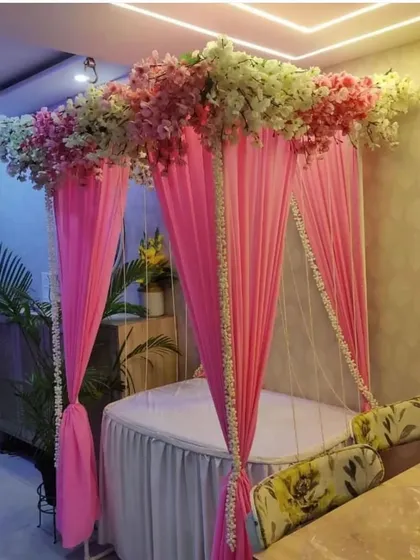 A simple and sweet canopy decoration with pink drapes and a floral border. This design is perfect for small home pujas or as a decorative element for any festival.