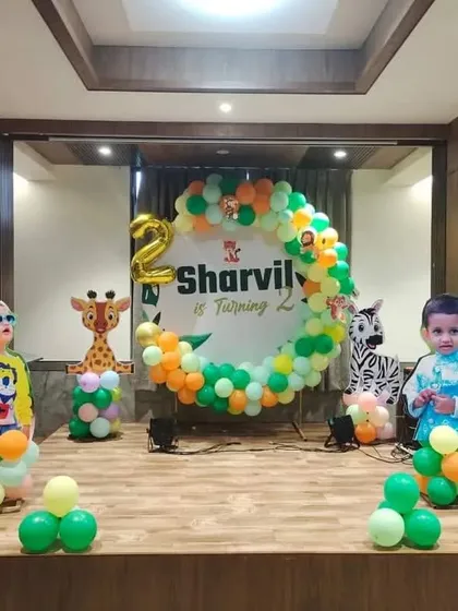A fun stage setup for a jungle-themed second birthday. This decoration features multiple character cutouts including a monkey and elephant, surrounding a personalized circular backdrop.