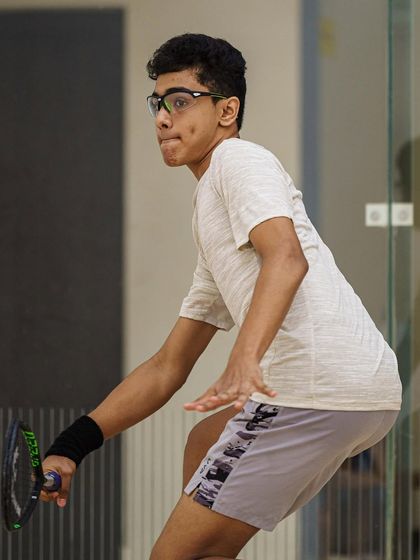 Abdus Samad is captured in the middle of a complex shot. His body position and focused gaze demonstrate the high level of technique required for competitive squash.