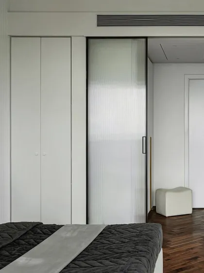 The master bedroom in our 2,700 sq.ft. apartment project features a fluted glass sliding door that separates the sleeping area from the walk-in wardrobe, adding a layer of privacy while allowing light to filter through.