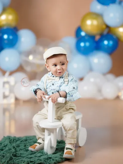 This little boy looks so dapper in his newsboy cap and overalls, ready to celebrate his first birthday with a blue and gold balloon theme.