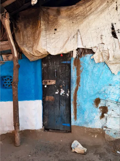 A rustic door on a bright blue wall, patched with tarpaulin. I find so much beauty in these makeshift, lived-in spaces.