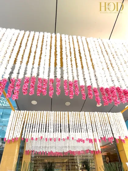 Looking up at the ceiling of the entrance, covered in strings of white and pink flowers, a truly immersive floral experience.