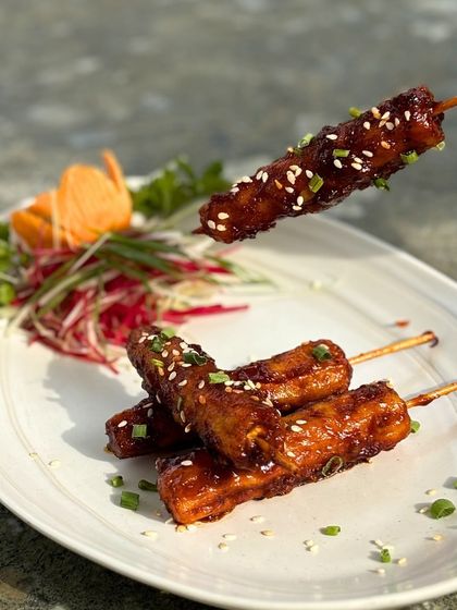 A close-up of our delicious chicken skewers, glazed and topped with sesame seeds.