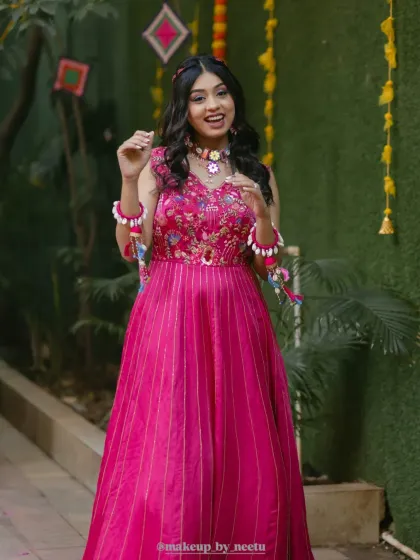 The Haldi ceremony is all about fun, color, and brightness. This soft glam look features a pop of pink on the dress, complemented by fresh, dewy makeup and playful floral jewelry. Her hair is styled in loose curls to keep the vibe relaxed and joyful.