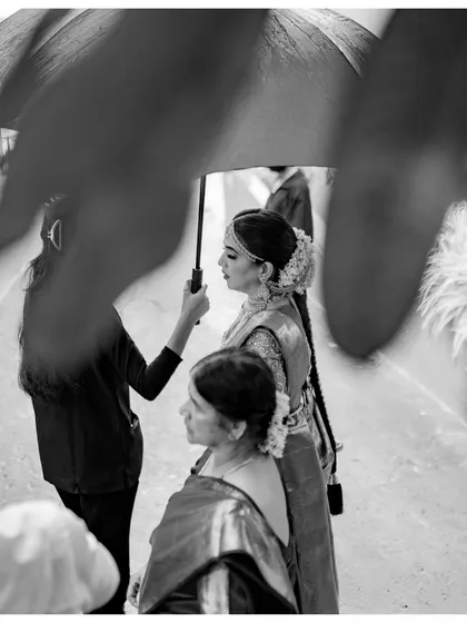 A beautifully framed black and white shot of the bride under an umbrella, capturing a quiet, cinematic moment.