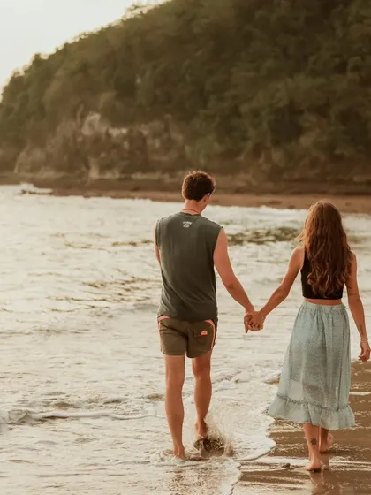 A couple walks hand-in-hand along the water's edge in Bali. This classic romantic shot captures the beginning of their journey together in a beautiful destination.