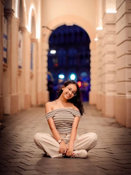 A cross-legged seated pose that feels relaxed and natural. The archway in the background frames her beautifully.