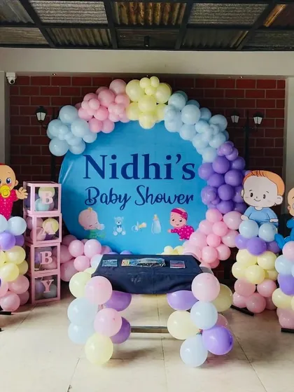 A cute baby shower setup with a custom backdrop and cartoon baby cutouts. The pastel balloons and 'BABY' blocks are perfect for the occasion.