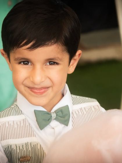 The birthday boy, looking sharp in his bow tie, enjoys some cotton candy. Capturing these small details helps to tell the complete story of the day.