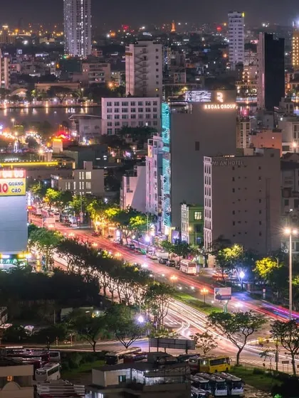 A wide-angle view of a bustling Vietnamese city at night, capturing the energy of the streets and the glow of the buildings.