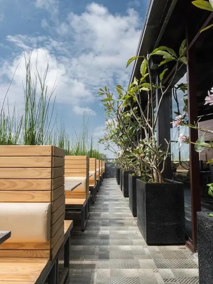 A hint of nature makes everything better. This rooftop seating area is lined with wooden planters filled with flowering trees and tall grasses, creating a natural screen and a garden-like atmosphere.