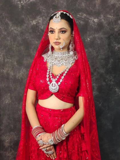 A striking look featuring a heavy, multi-layered American Diamond necklace set against a bright red lehenga. This is perfect for a bride who wants maximum sparkle.