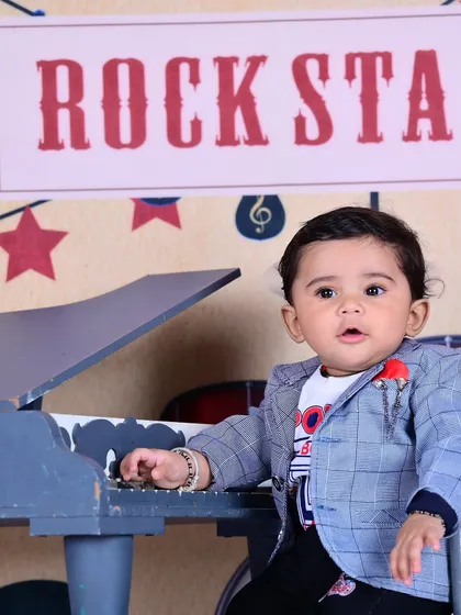 A little "Rock Star" at a miniature piano, looking cool and confident.