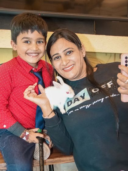 A fun and unique moment at a party where a boy and his mother pose with a small white rabbit.