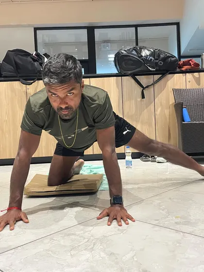 A focused moment of practice for Rohan Bopanna. This image captures the dedication and intensity that athletes bring to their yoga practice, treating it as an integral part of their training regimen.