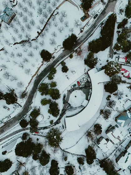 A view from my DJI Mini 4 Pro. I love using my drone to capture the sheer scale and patterns of a landscape, like this stunning top-down aerial of a snow-covered village and winding road.