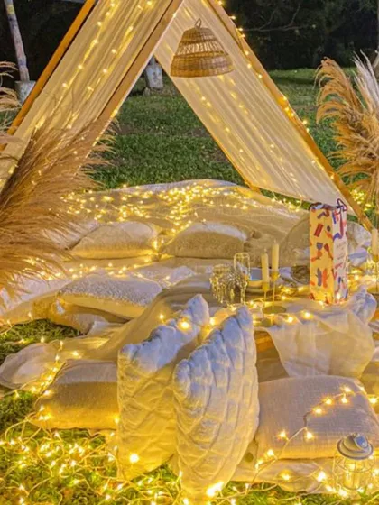 A dreamy and romantic teepee setup, perfect for a proposal or an intimate date night. The entire space is illuminated with a dense web of fairy lights, creating a truly magical escape.