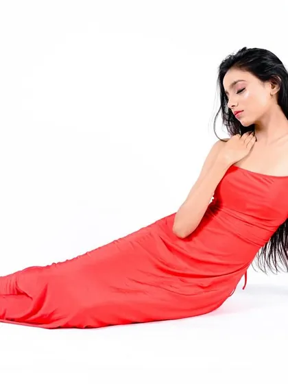 A reclining pose that showcases the full length of the dress and creates an elegant, high-fashion silhouette against the clean white background.