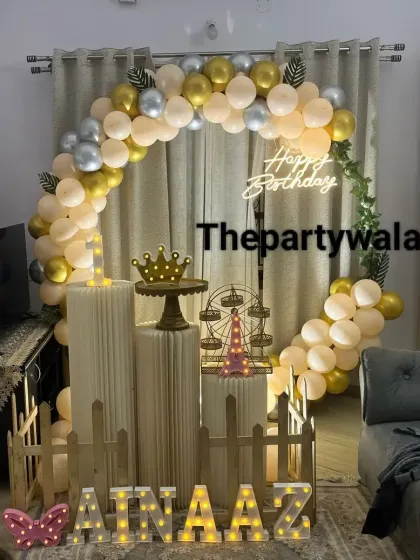 An elegant at-home birthday setup with a gold, silver, and cream balloon arch. The decorations are arranged to fit beautifully within the living room space.