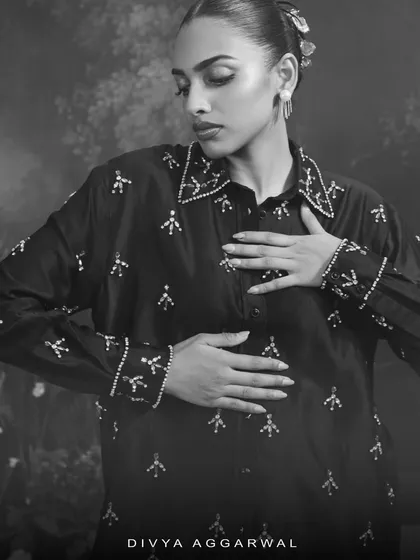 This black and white image of the Astra shirt highlights the delicate, shimmering embellishments against the dark fabric, creating a celestial, starry effect.