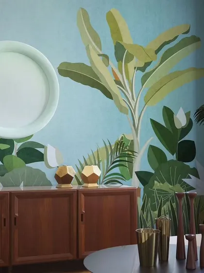 This design shows how a stylized, graphic tropical wallpaper can complement mid-century modern furniture. The bold green leaves against a solid blue background create a chic and artistic statement.