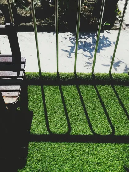 Even a small balcony can become a green escape. Here, the artificial turf adds a touch of nature and comfort, creating a pleasant space to sit and enjoy the outdoors. The shadows from the railing add a nice graphic element.