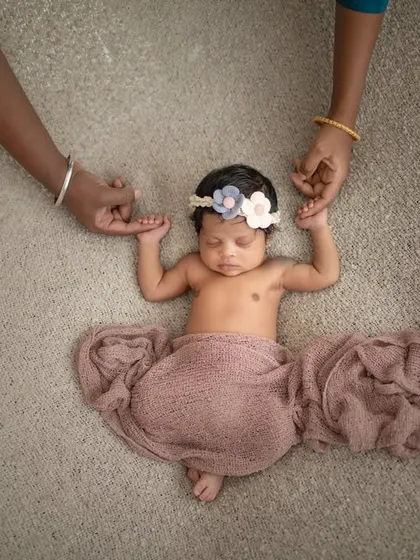 Parents' hands gently holding their new baby. This pose is a beautiful way to show the love and connection of a new family.