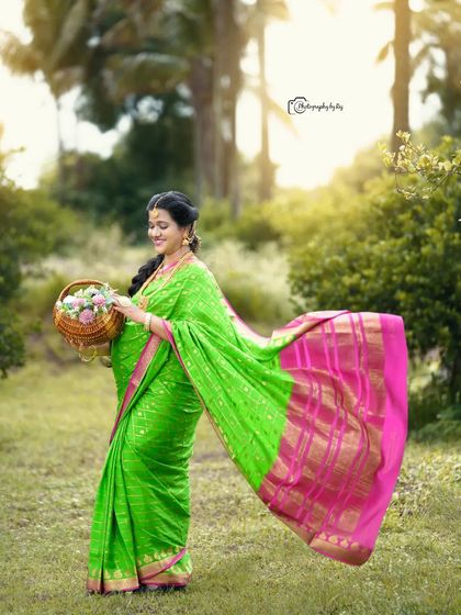 A graceful outdoor portrait of a mother-to-be in a bright green and pink saree, holding a basket of flowers.