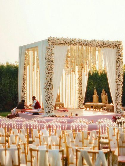 An outdoor wedding mandap with a stunning view. The structure is decorated with white flowers and drapes, creating a serene and elegant space for the ceremony.