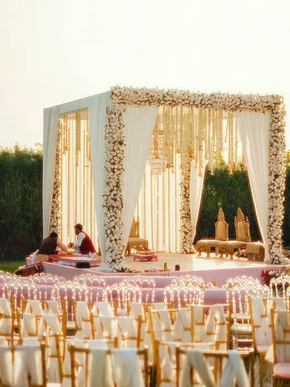 An outdoor wedding mandap with a stunning view. The structure is decorated with white flowers and drapes, creating a serene and elegant space for the ceremony.