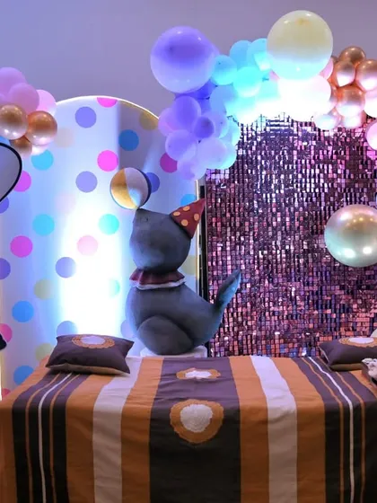 A different view of the pastel circus setup, showing the cake table area with a giraffe prop and a sequin backdrop.