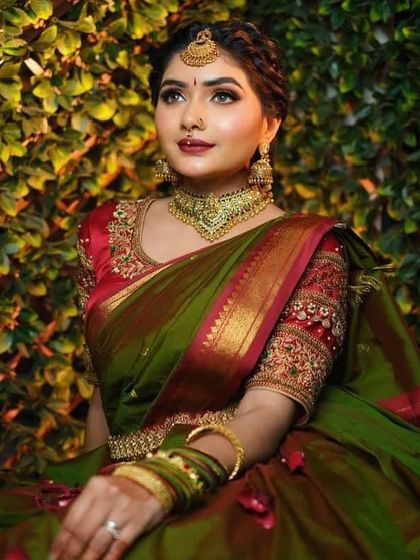 A stunning portrait of a South Indian bride. The olive green and red Kanjivaram, paired with a choker and traditional jewelry, creates a look of timeless beauty.