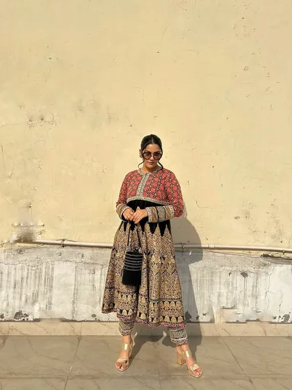 This full-length view demonstrates the balance of the outfit, with the compact potli providing a sleek counterpoint to the voluminous dress.
