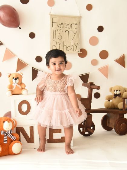 That beautiful smile says it all. This first birthday portrait captures a moment of pure happiness amidst a charming teddy bear party setup.