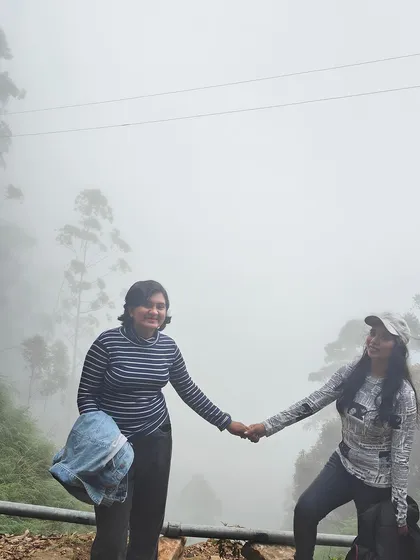 Two friends holding hands in the misty Kodaikanal hills.