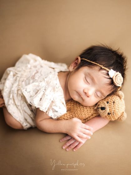 Cuddling with a tiny teddy bear. Using simple props like a small stuffed animal can add a touch of sweetness and scale to the portrait.