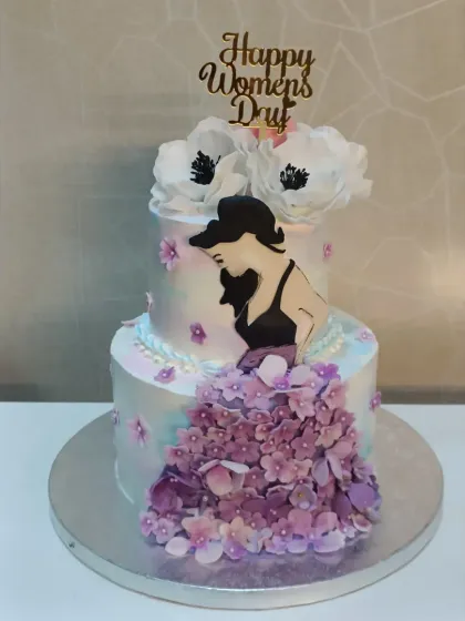 An elegant cake for Women's Day. This two-tiered design features a silhouette of a woman and a cascade of purple sugar flowers.