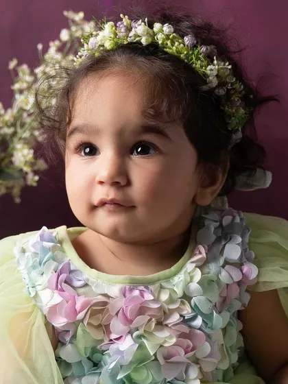 A stunning close-up portrait of the birthday girl. The details of her floral dress and crown are highlighted against the soft, colorful background.